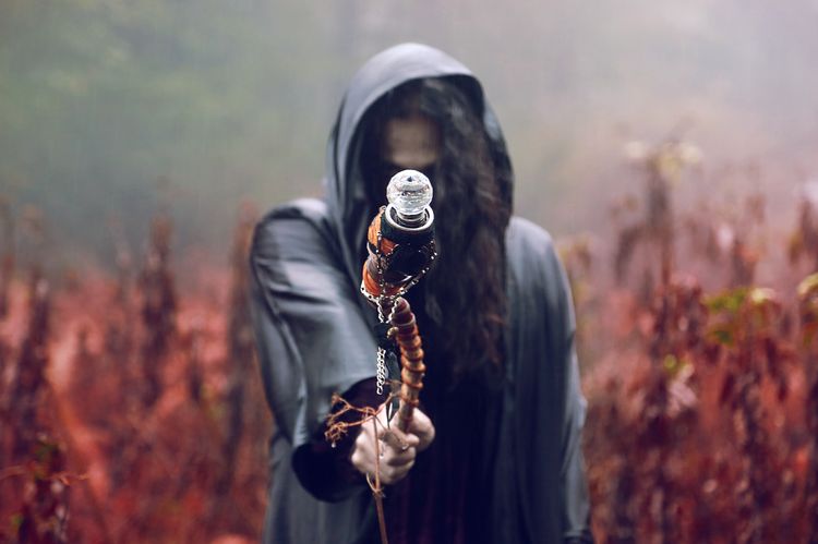Hooded figure holding a staff in a misty forest